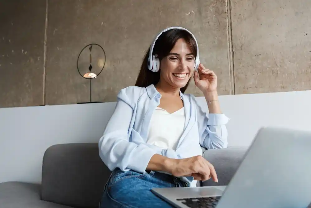 Happy woman wearing headphones, using laptop, working from home