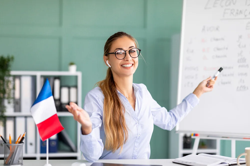 Happy french teacher giving online lesson, holding marker and french flag.