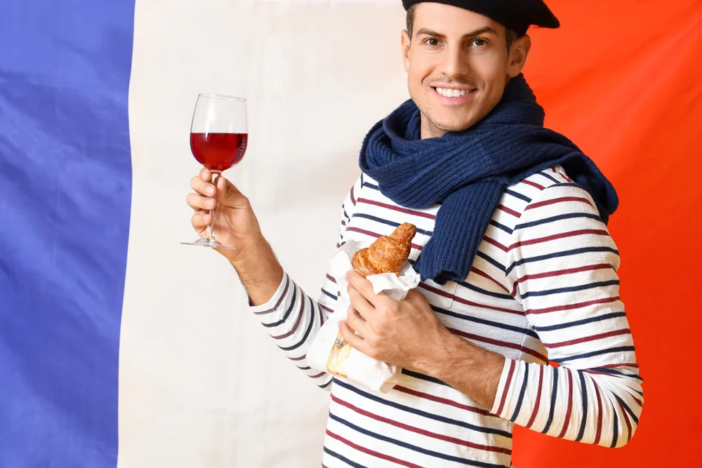 Man in beret enjoys french wine and croissant