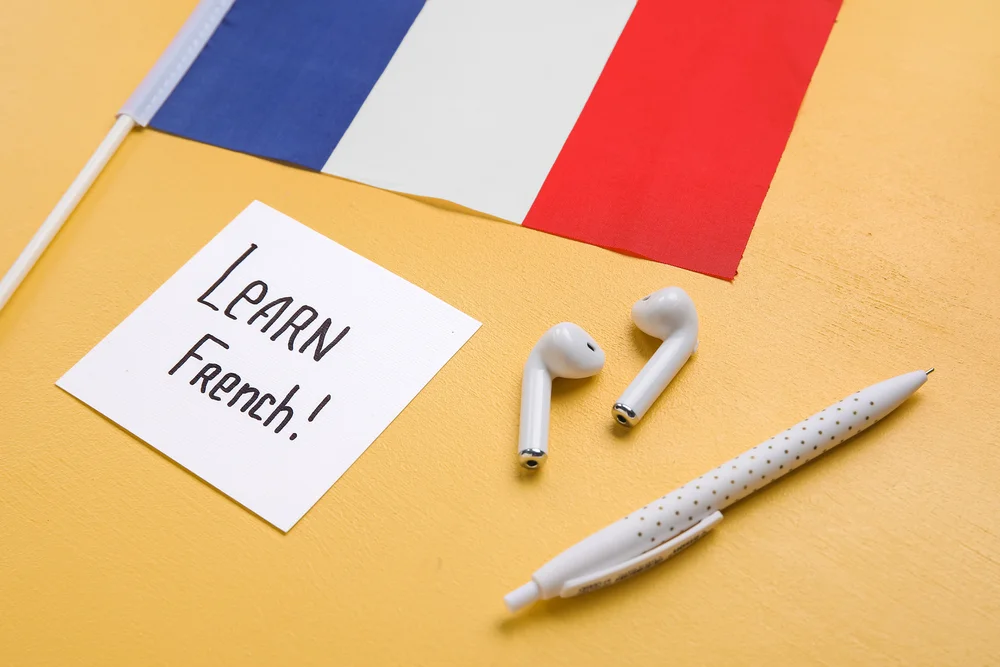 Learn french! note with french flag, earbuds, and pen.