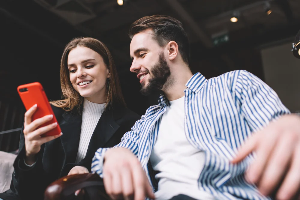 Couple looking at smartphone together, smiling.