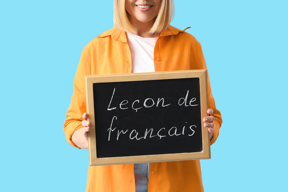 Woman holding a french lesson chalkboard; "leçon de français